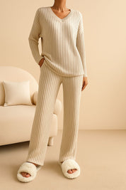 Tan ribbed knit V-neck lounge set with relaxed sweater and straight-leg pants, soft medium-weight knit — front view (sofa scene).