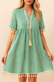 turquoise-geometric-print-tassel-trim-mini-dress-tassel-hem-empire-seam-front-view-holding-hem