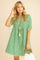 Women’s turquoise geometric-print tassel-trim mini dress with tassel-tie split neckline and short sleeves — front view.