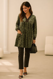 Woman wearing a khaki velvet dress styled with black pants, heels, and a handbag for a modern casual outfit