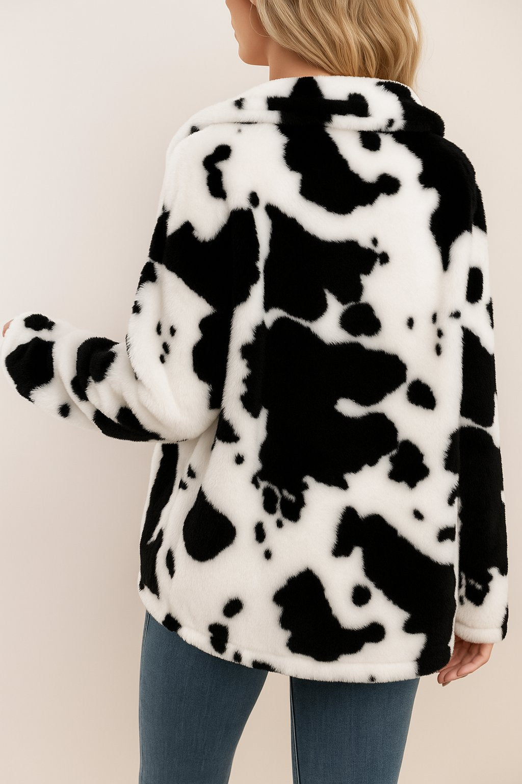 Back view of the white and black cow-print fuzzy jacket showing the overall pattern and rounded hem.