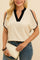 Front view of a white cold-shoulder blouse with contrast black trim and a notched V-neck; smooth woven hand and relaxed everyday fit.