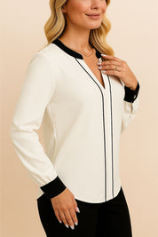 Right three-quarter view of the white blouse with black contrast trim at the neckline and cuffs; smooth drape