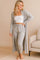 Woman wearing a soft gray loungewear set with cardigan, jogger pants, and white bandeau top in cozy home interior